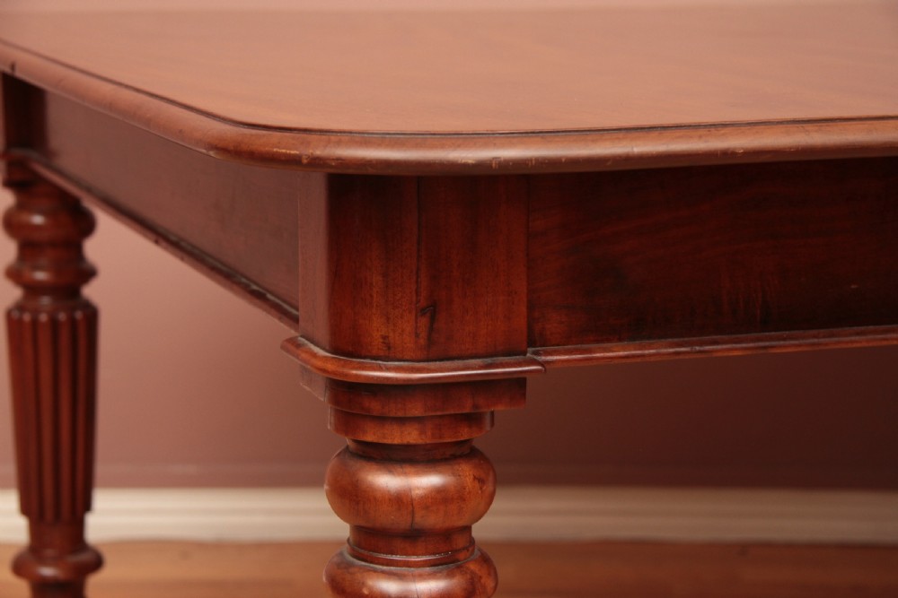 A extended Cuban mahogany dining table featuring additional insert leaves, a polished rectangular top, and four reeded turned legs on brass castors. View XIV