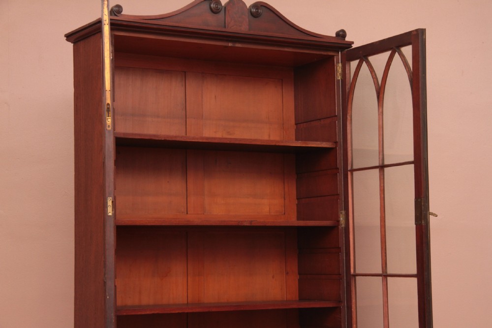 An antique dark mahogany bureau bookcase featuring a shaped pediment, twin astragal glazed doors, and four lower drawers with oval brass handles. View X