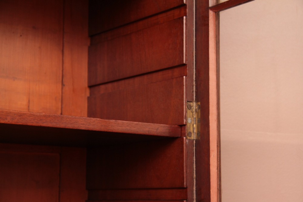 An antique dark mahogany bureau bookcase featuring a shaped pediment, twin astragal glazed doors, and four lower drawers with oval brass handles. View XI