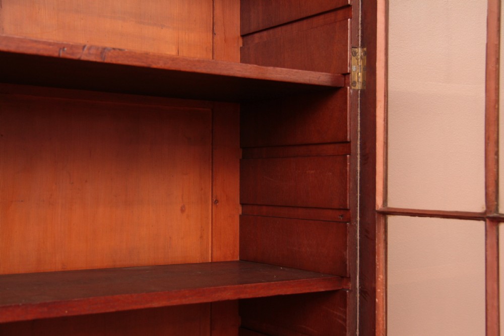 An antique dark mahogany bureau bookcase featuring a shaped pediment, twin astragal glazed doors, and four lower drawers with oval brass handles. View XII