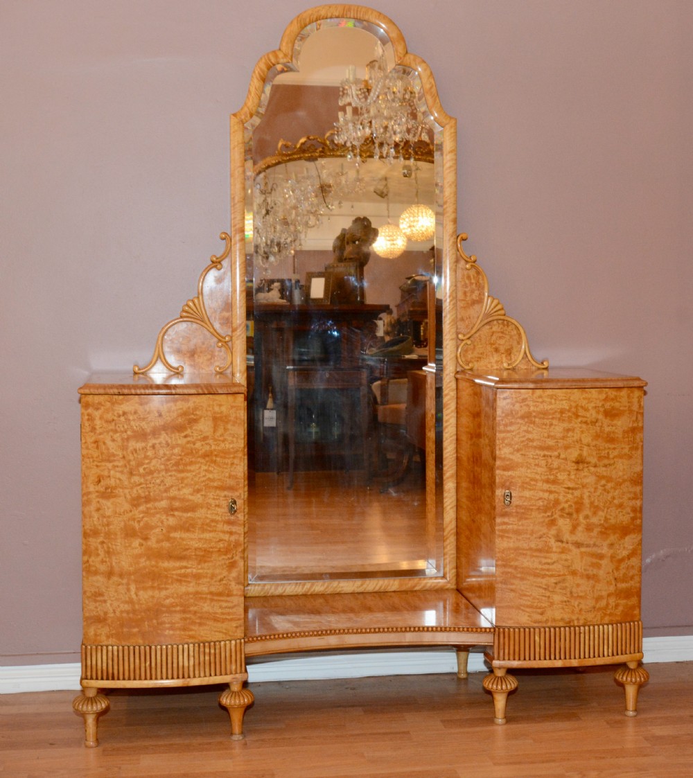 A Swedish satin birch dressing table featuring a tall central arched mirror flanked by two side pedestals with carved scroll brackets and reeded feet.