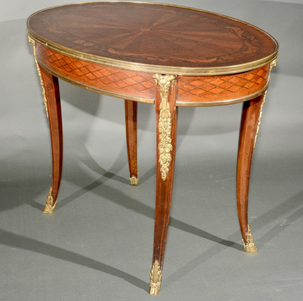 A 19th-century French Louis XV style oval centre table featuring sunburst and diaper marquetry, polished gilt bronze rim and mounts, resting on curved legs ending in hoof feet. View II