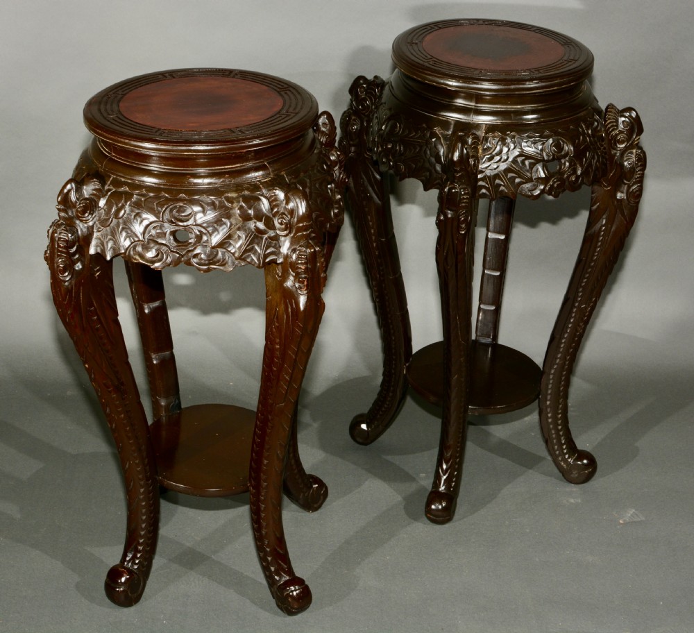 A pair of dark wood carved Asian plant stands featuring round inset tops, openwork aprons, cabriole legs, and lower circular shelves. View II