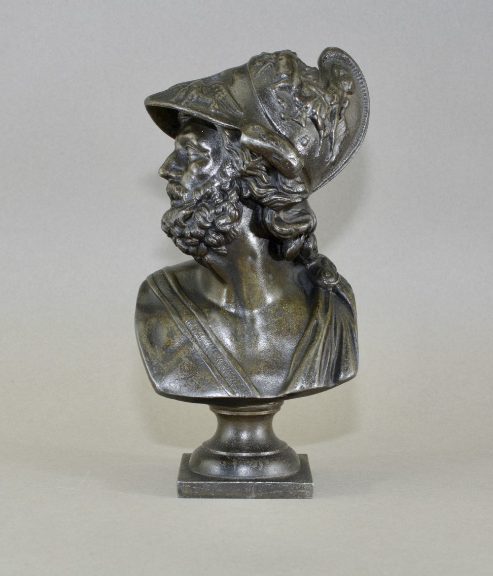 A 19th-century patinated bronze bust depicting King Menelaus wearing a helmet and draped classical garments, mounted on a square base.