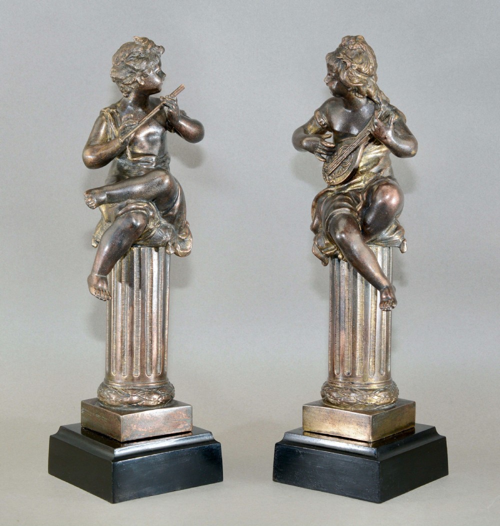 A pair of mid-19th-century bronze sculptures featuring cherubs playing musical instruments while seated atop fluted columns. View II
