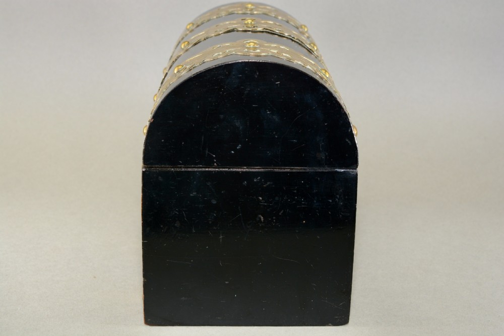 A dark coromandel wood domed stationery box decorated with intricate engraved brass straps and central keyhole. View V