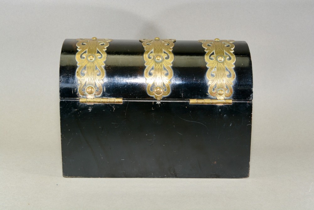 A dark coromandel wood domed stationery box decorated with intricate engraved brass straps and central keyhole. View VI