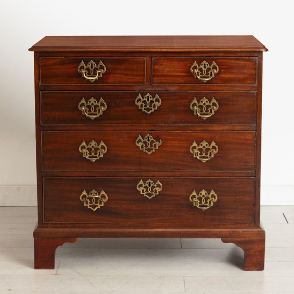 A Georgian mahogany chest of drawers featuring two short drawers over three long graduated drawers with decorative brass handles and bracket feet.