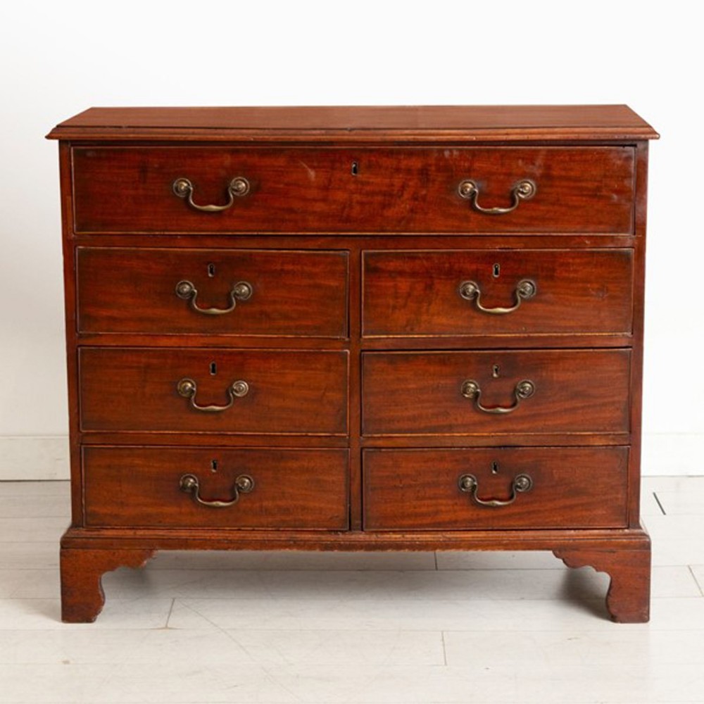 A Georgian mahogany chest of drawers featuring seven drawers with brass swan-neck handles and bracket feet.