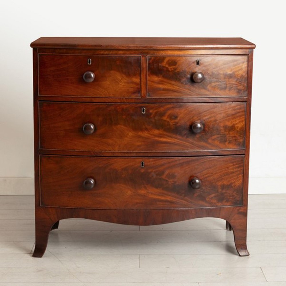 A Victorian mahogany bow-fronted chest of drawers featuring two short drawers over two long graduated drawers with turned wooden knobs and splayed bracket feet.
