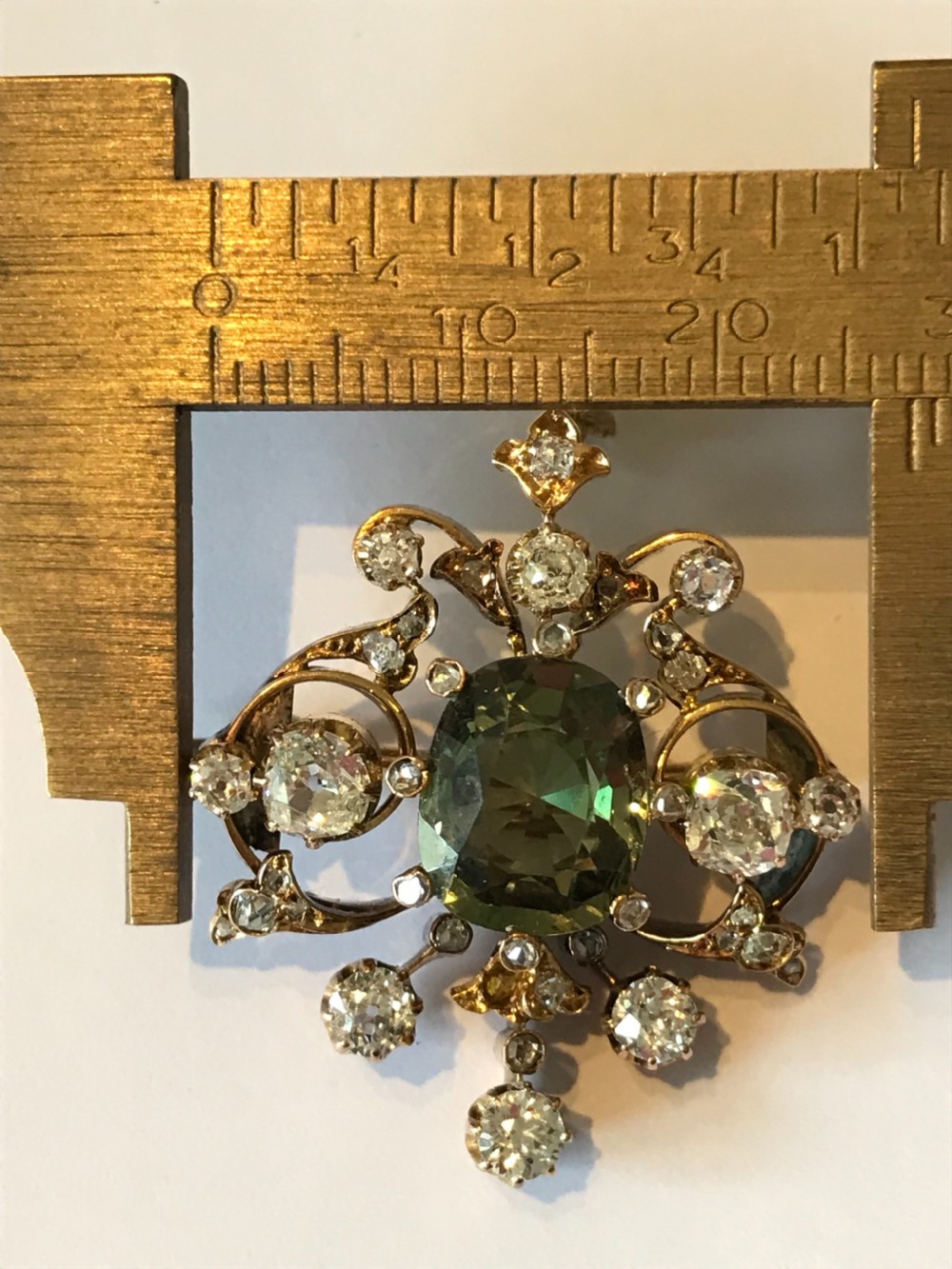 A Victorian gold pendant featuring a central cushion-cut green sapphire within an openwork diamond-set scrollwork frame. View III