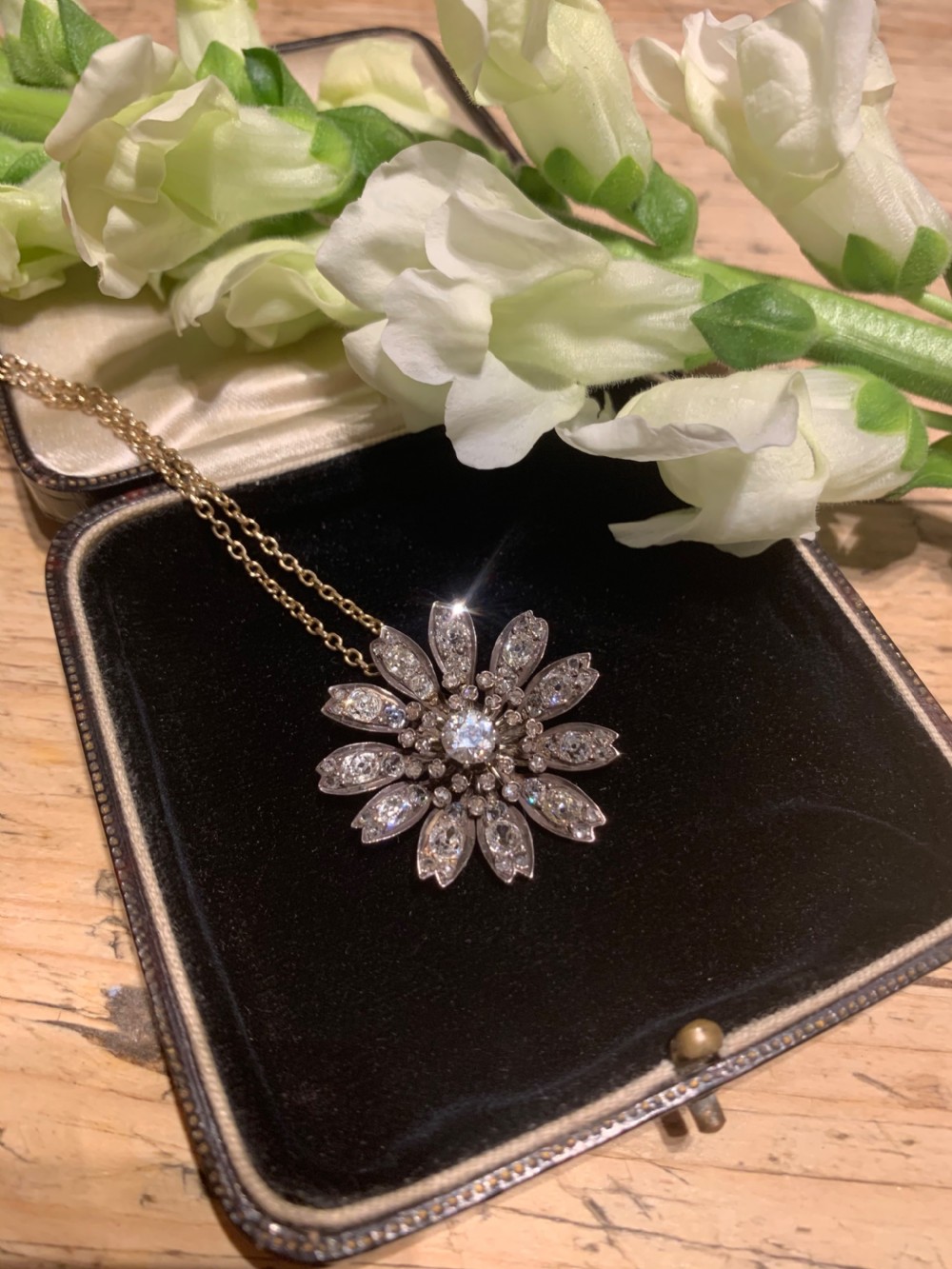 A Victorian diamond flower-shaped pendant featuring old cut and rose cut diamonds set in silver and gold suspended on a fine chain. View II