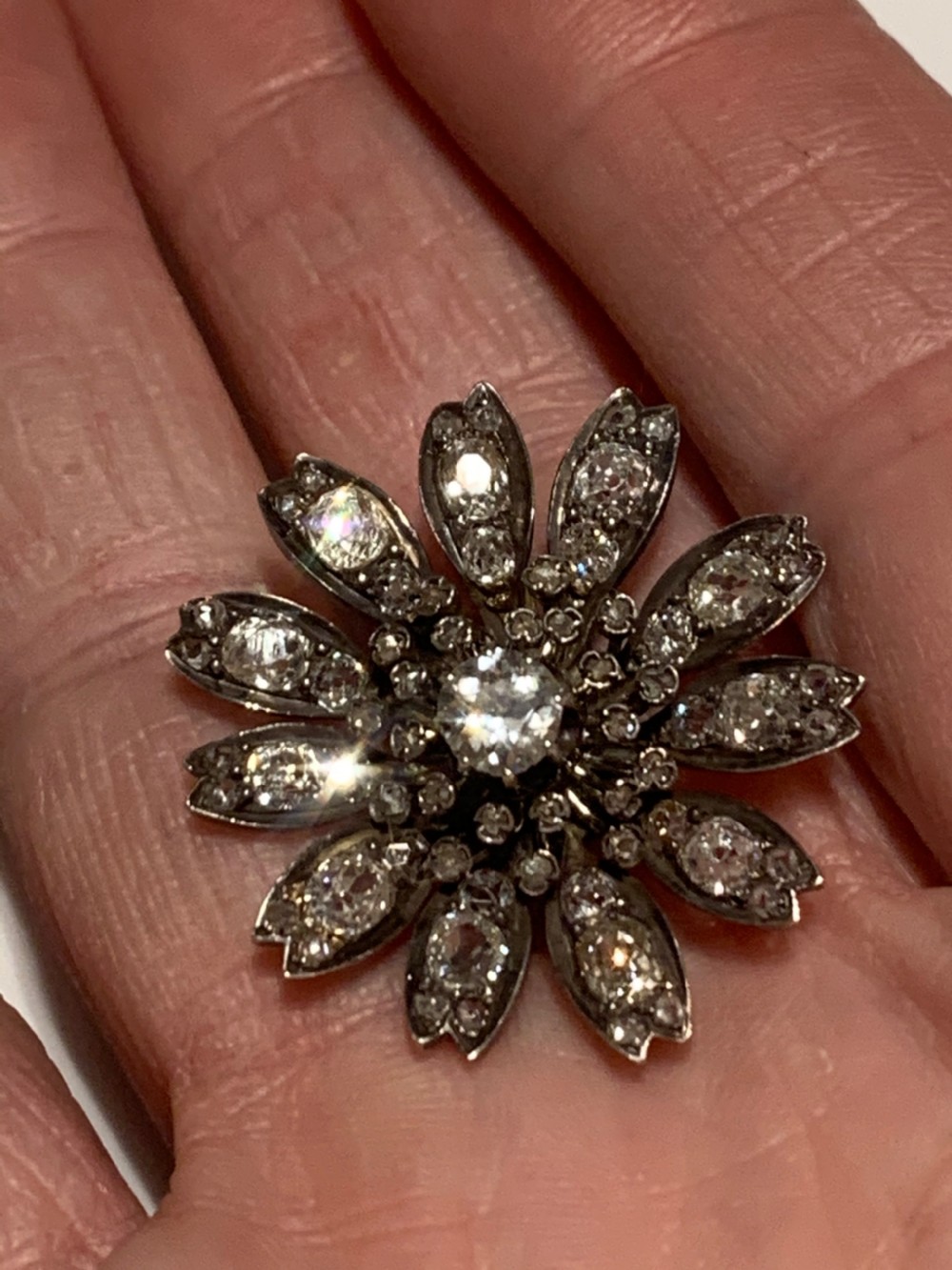A Victorian diamond flower-shaped pendant featuring old cut and rose cut diamonds set in silver and gold suspended on a fine chain. View VII