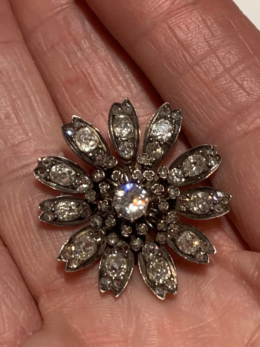 A Victorian diamond flower-shaped pendant featuring old cut and rose cut diamonds set in silver and gold suspended on a fine chain. View IX