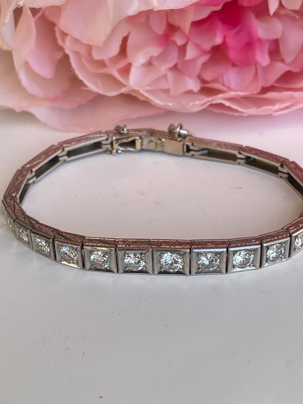 A mid-twentieth-century white gold line bracelet featuring round diamonds set within square box links with hand-engraved side details.