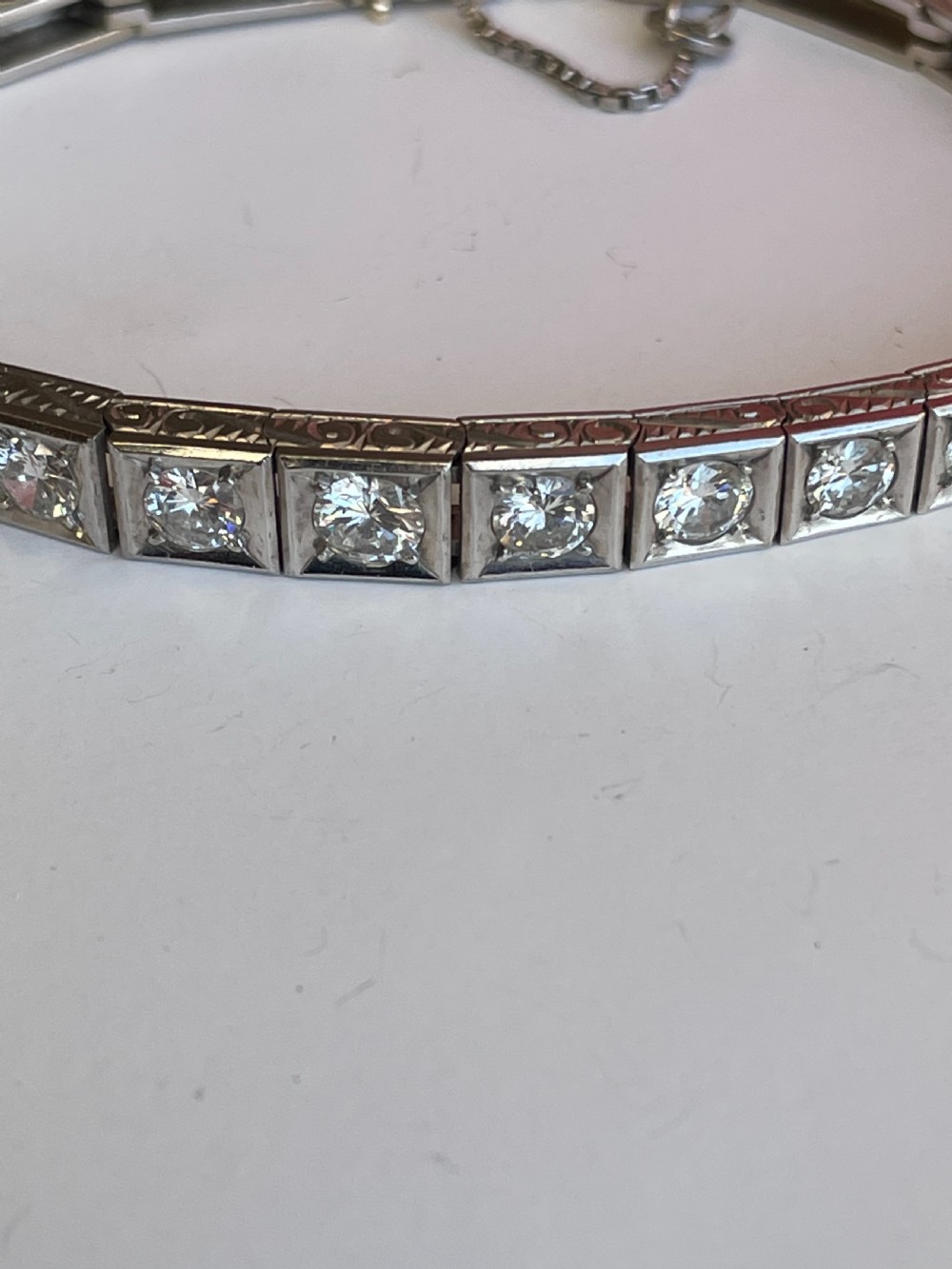 A mid-twentieth-century white gold line bracelet featuring round diamonds set within square box links with hand-engraved side details. View III