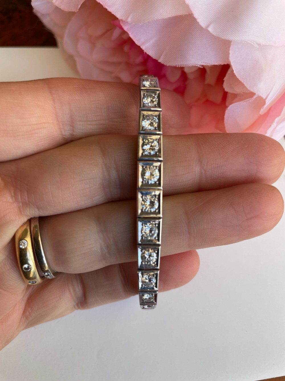A mid-twentieth-century white gold line bracelet featuring round diamonds set within square box links with hand-engraved side details. View IV