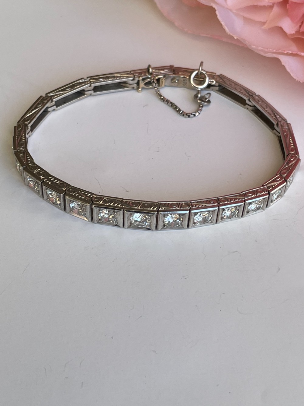 A mid-twentieth-century white gold line bracelet featuring round diamonds set within square box links with hand-engraved side details. View V