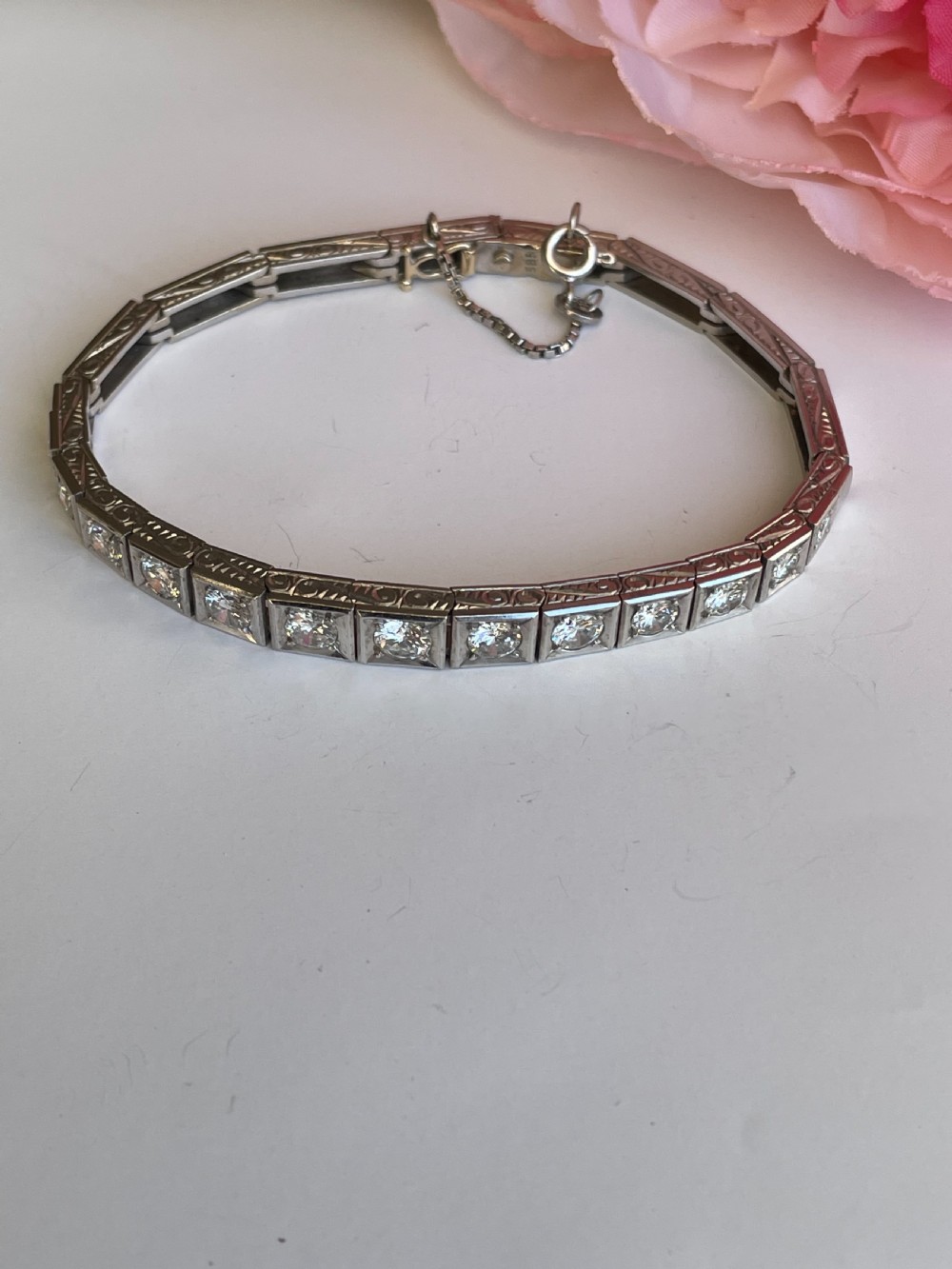 A mid-twentieth-century white gold line bracelet featuring round diamonds set within square box links with hand-engraved side details. View VI
