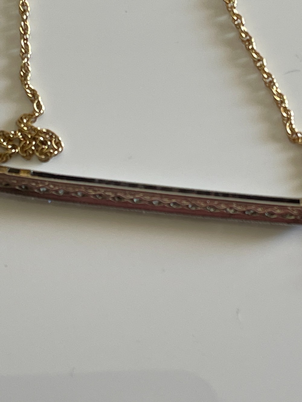 An antique platinum bar set with a row of diamonds suspended from a fine gold chain. View III