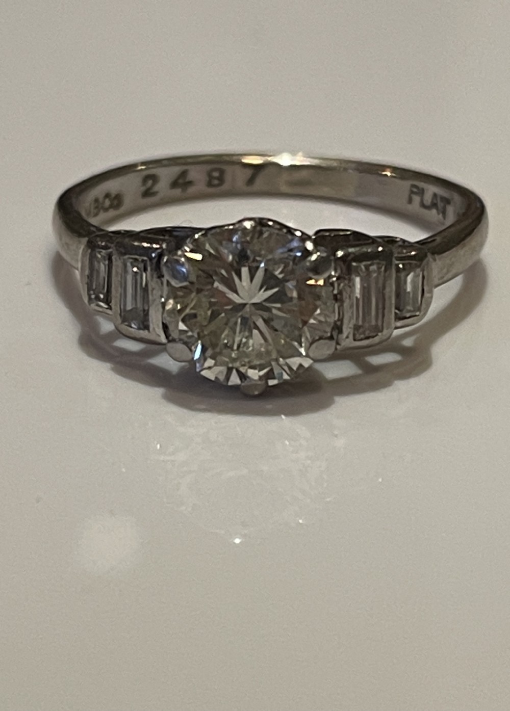 An Art Deco diamond engagement ring with a central round brilliant diamond flanked by stepped baguette shoulder diamonds in a white metal mount. View III
