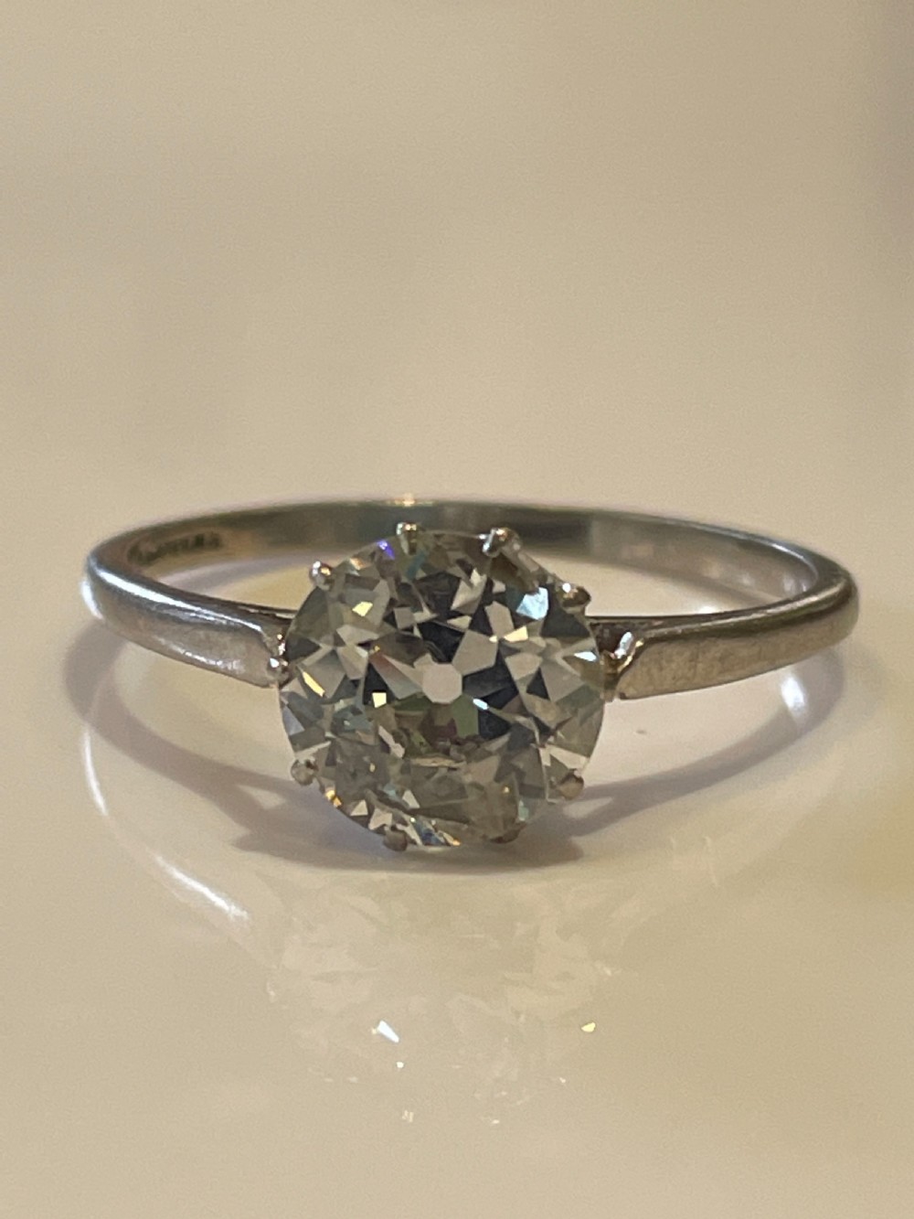 An antique diamond solitaire ring featuring a round old-cut diamond set in an eight-claw white metal mount.