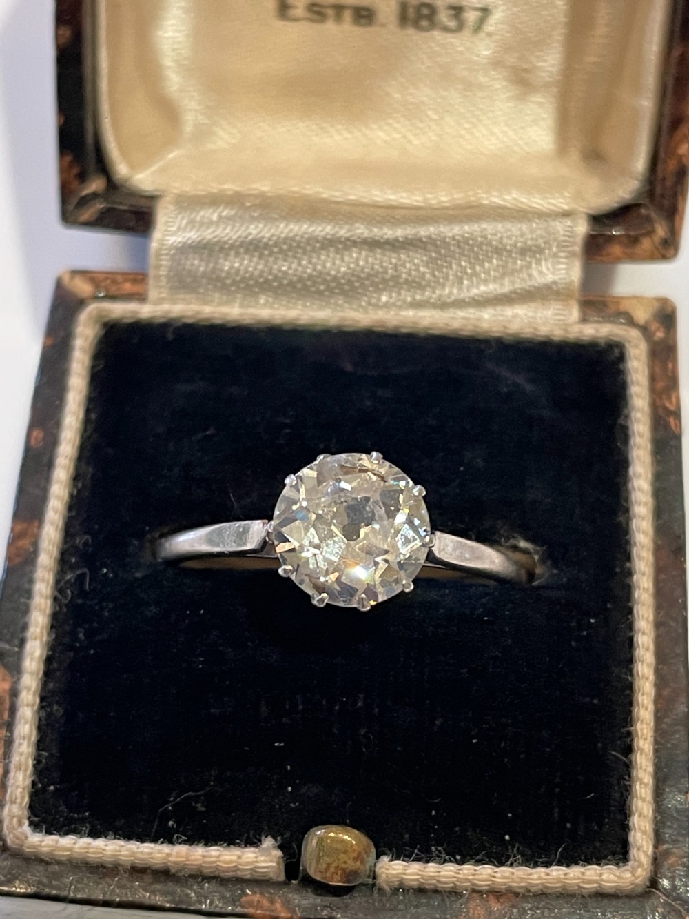 An antique diamond solitaire ring featuring a round old-cut diamond set in an eight-claw white metal mount. View V