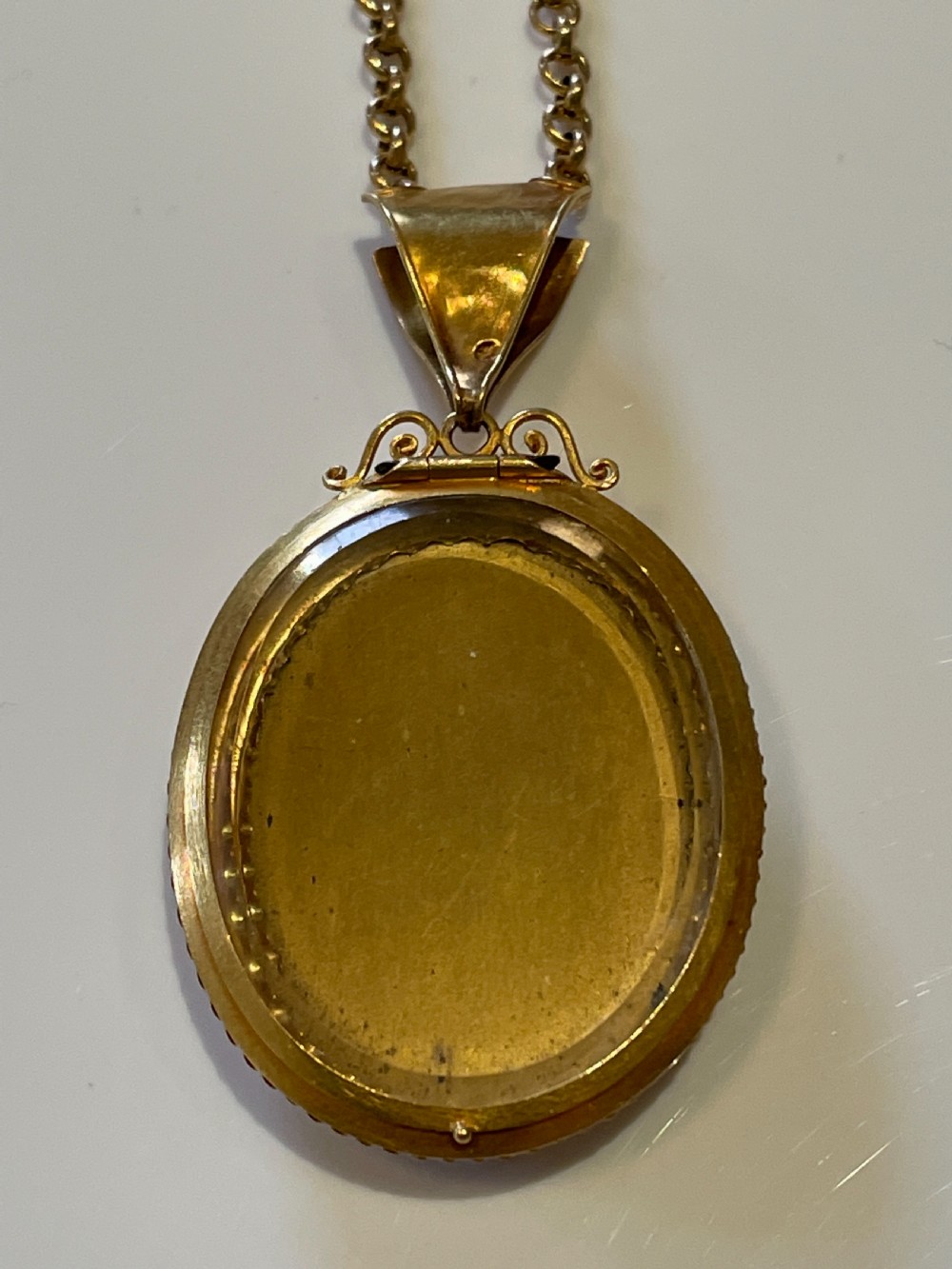 An oval 18ct yellow gold pendant featuring a black Pietra Dura hardstone inlay of pink and white roses suspended from a gold chain. View III