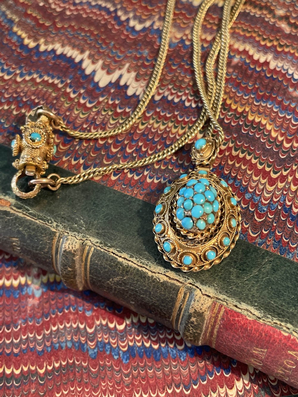 An early Victorian yellow gold chain featuring an oval pendant set with pave turquoise stones alongside a detailed matching turquoise clasp.
