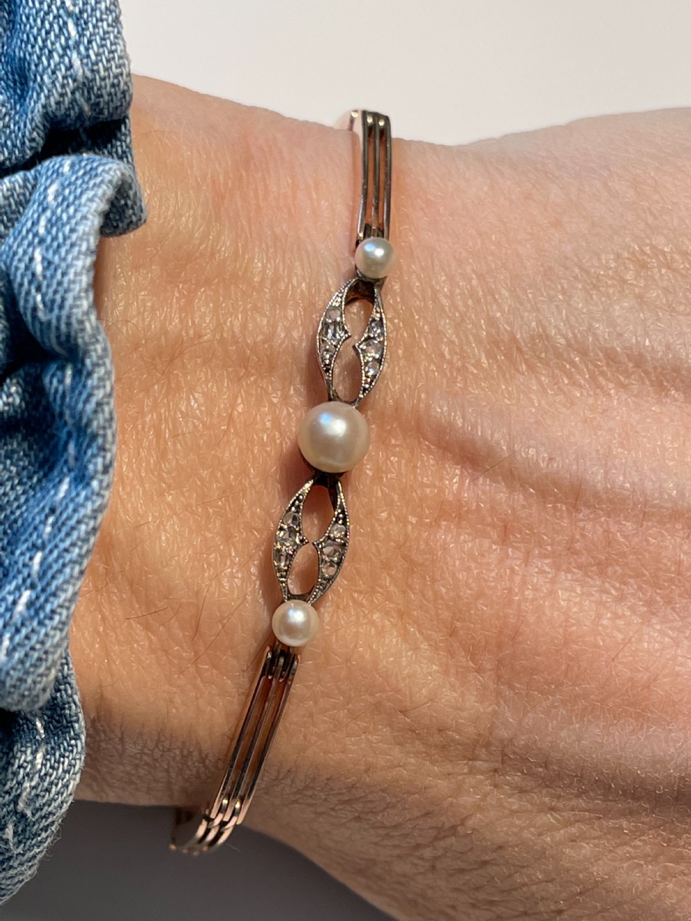 An Edwardian gold and platinum link bracelet featuring central pearls flanked by openwork diamond-set filigree motifs. View III
