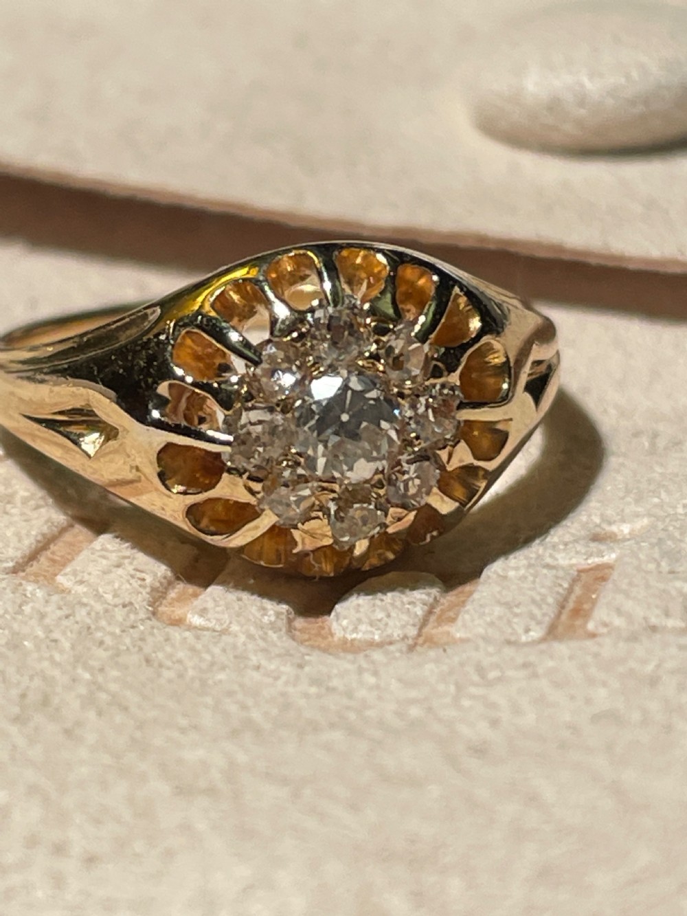 A Victorian yellow gold ring featuring a central cluster of old cut diamonds with carved detail along the shoulders.