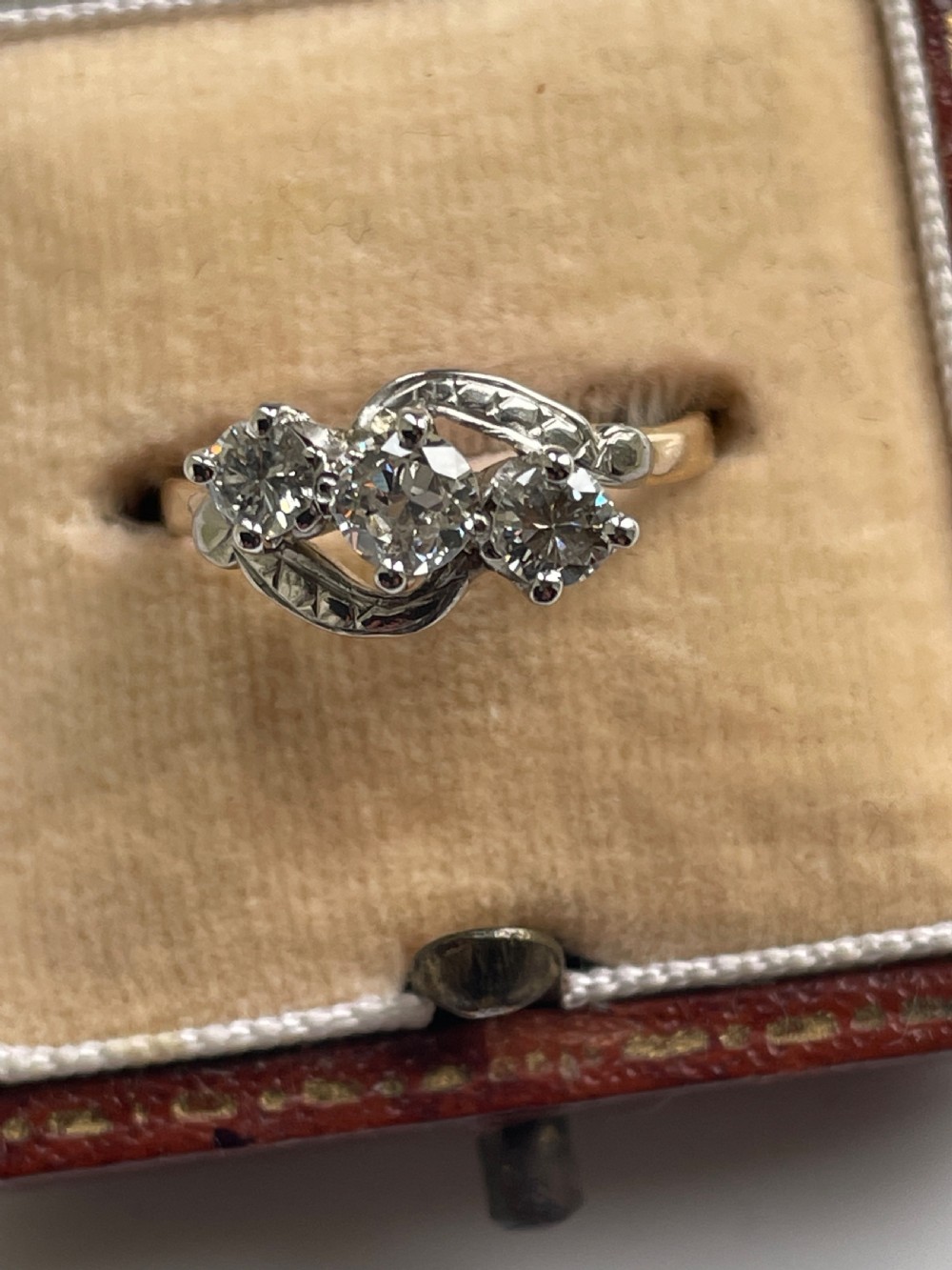 A 1940s three-stone diamond trilogy ring featuring round diamonds set diagonally in a crossover yellow gold and white metal band. View II