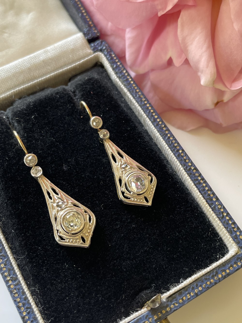A pair of Edwardian diamond drop earrings featuring openwork geometric filigree settings suspended from wire hooks. View II