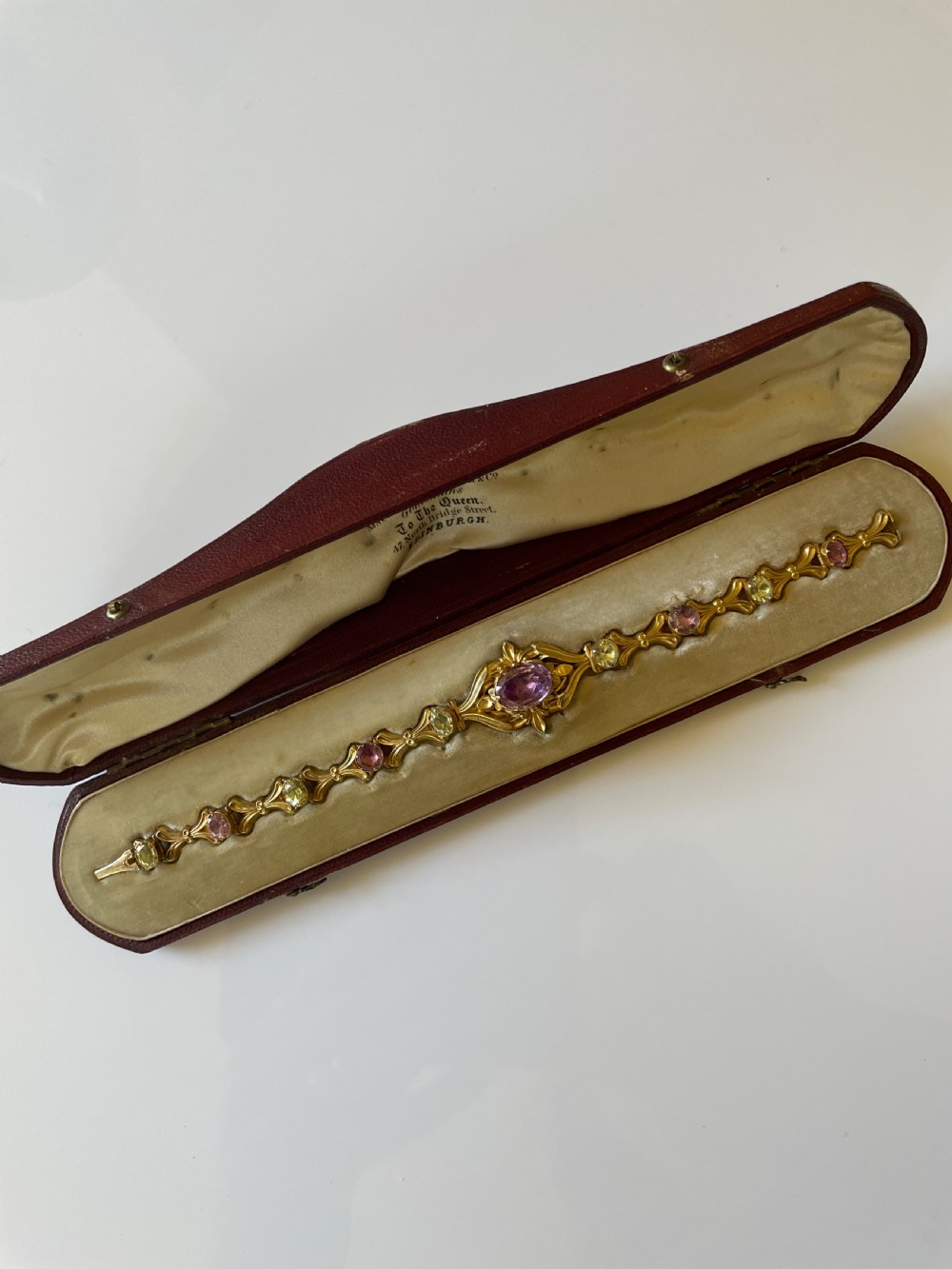 A Victorian gold link bracelet set with alternating oval chrysoberyl and amethyst gemstones, displayed inside an open fitted leather presentation box. View VII