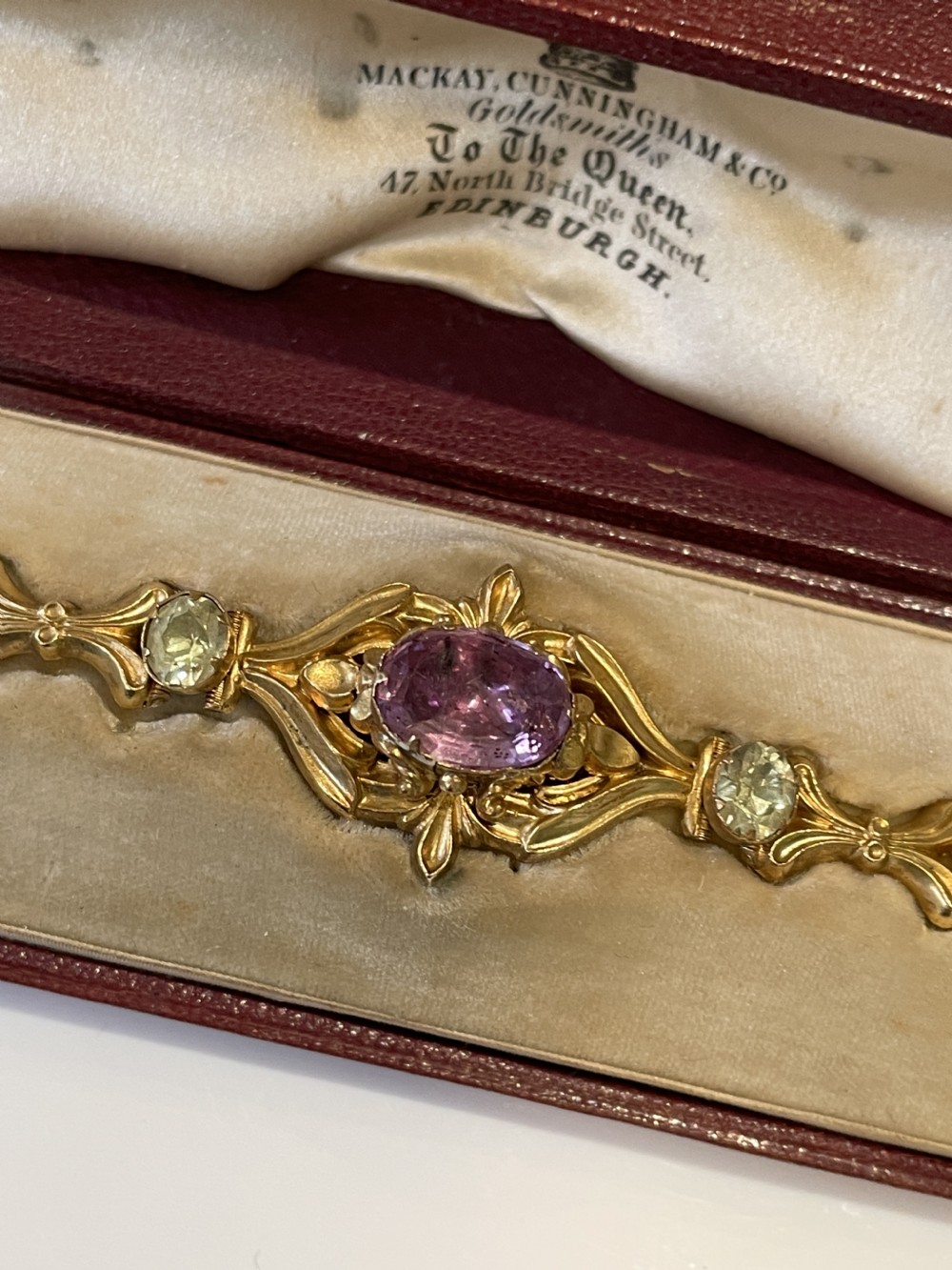 A Victorian gold link bracelet set with alternating oval chrysoberyl and amethyst gemstones, displayed inside an open fitted leather presentation box. View VIII