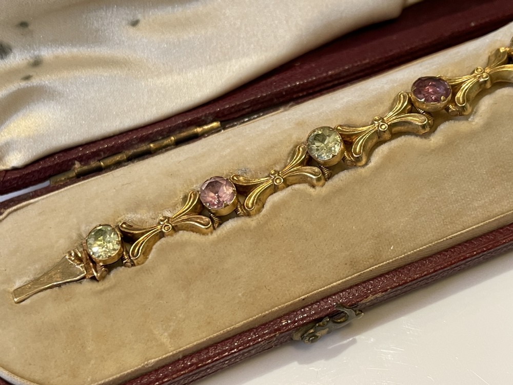 A Victorian gold link bracelet set with alternating oval chrysoberyl and amethyst gemstones, displayed inside an open fitted leather presentation box. View X