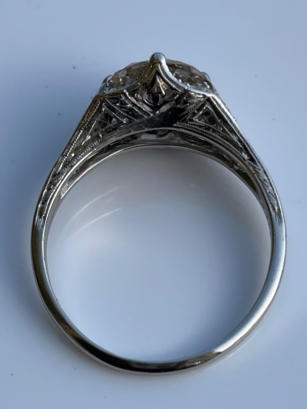 An Art Deco platinum ring featuring a large central round diamond with smaller accent diamonds and leaf motifs engraved into the shoulders. View III