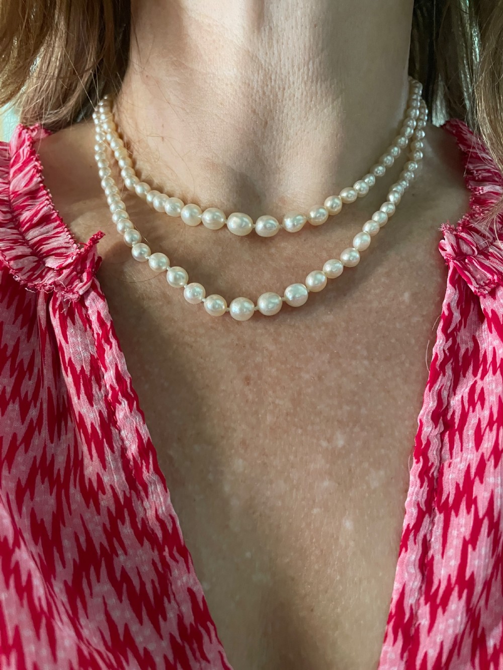 A double-strand cream pearl necklace displayed on a neck, featuring lustrous spherical pearls.