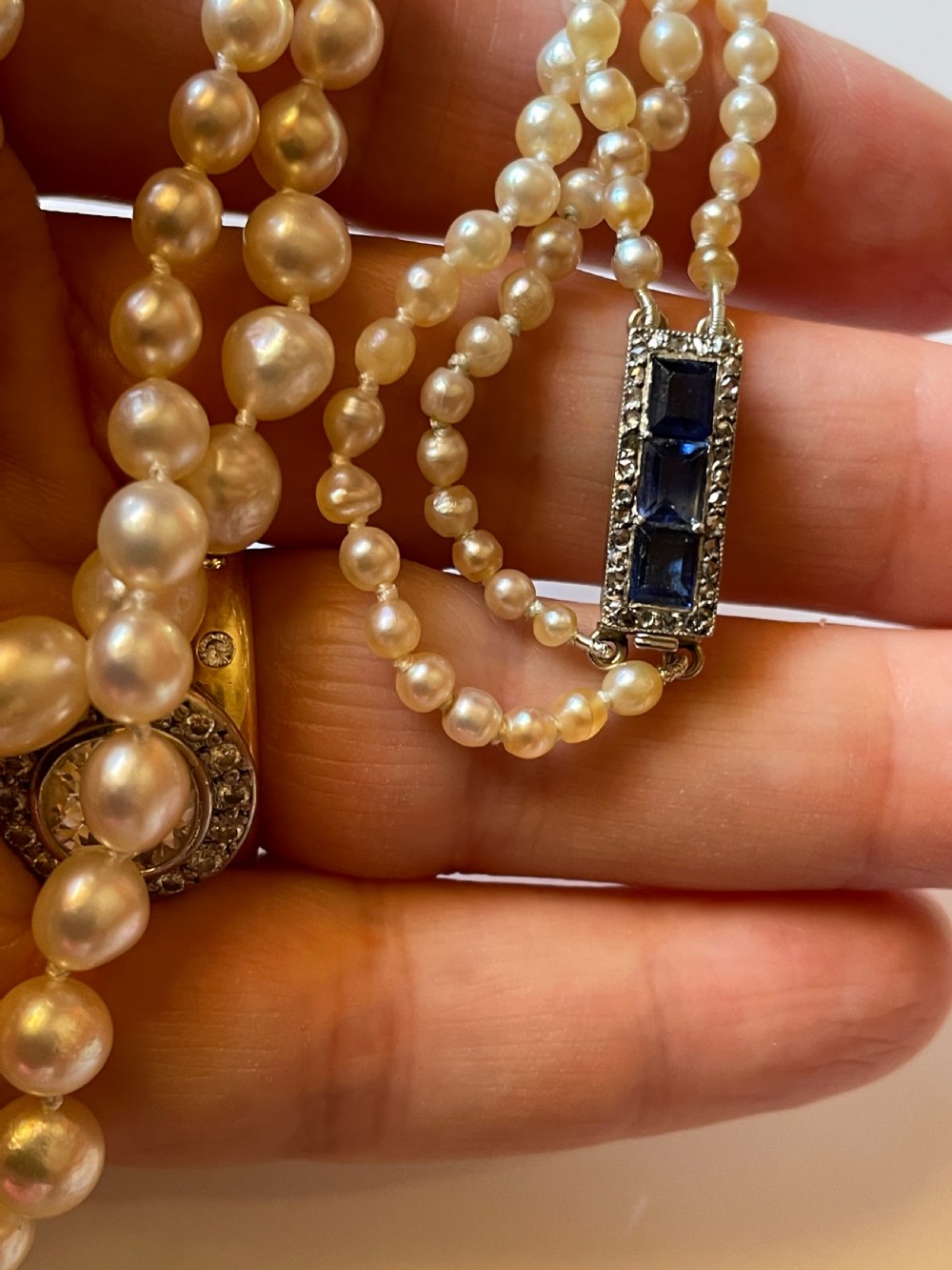 A double-strand cream pearl necklace displayed on a neck, featuring lustrous spherical pearls. View III