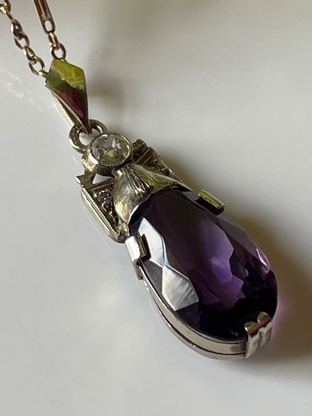An antique drop pendant featuring a large teardrop faceted purple amethyst suspended beneath a diamond-set white metal mount and bail. View III
