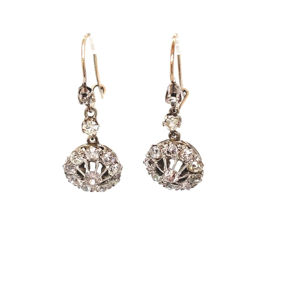 A pair of antique diamond drop earrings featuring old European cut diamonds set in round openwork cluster drops suspended from hook fittings.