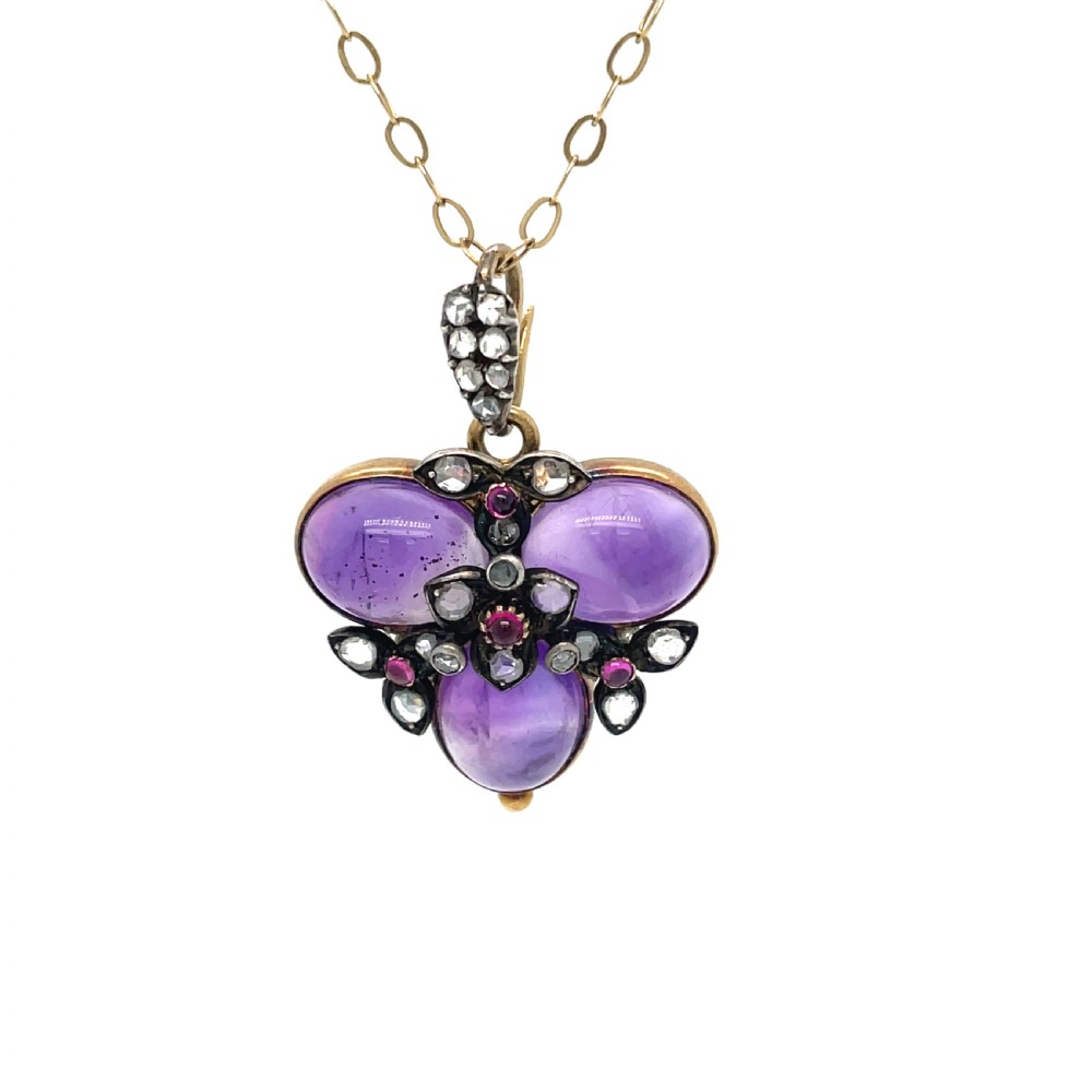 Victorian gold pendant featuring three smooth cabochon amethysts arranged in a trefoil motif, accented with diamonds and rubies, suspended on a gold rope chain. View III