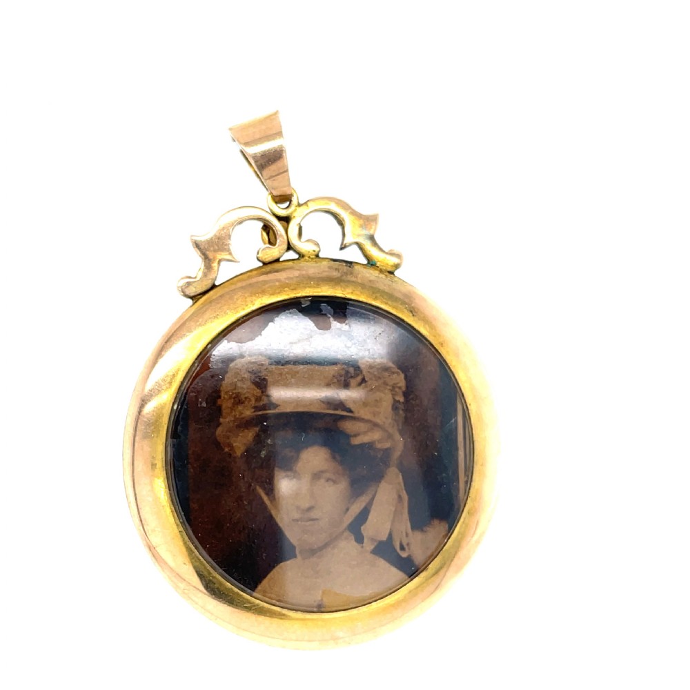 A circular Edwardian 9ct gold photograph locket framed with seed pearls, enclosing a miniature portrait under glass. View II