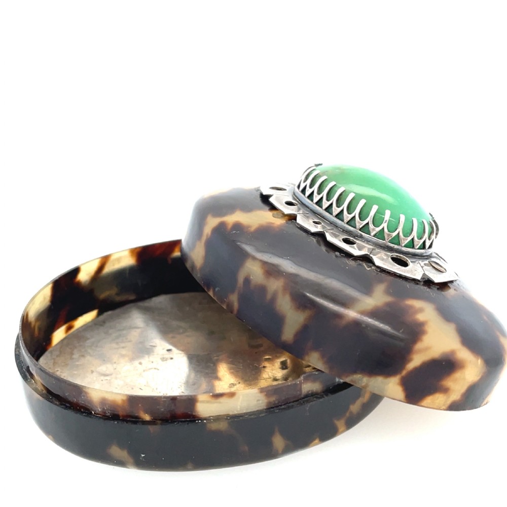 An oval dark brown tortoiseshell box featuring a polished green oval jadeite cabochon set in a silver mount on the lid. View II