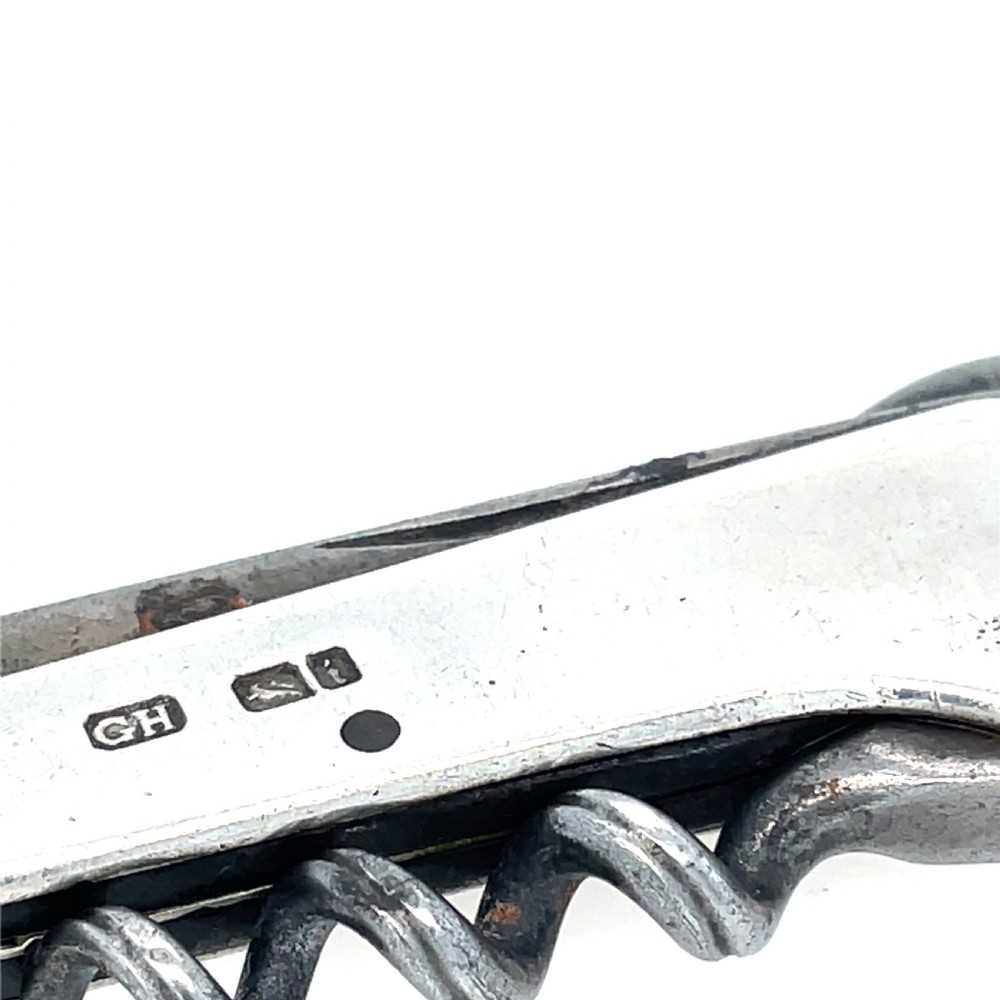 An antique sterling silver folding pocket corkscrew featuring visible hallmarks on its casing. View III
