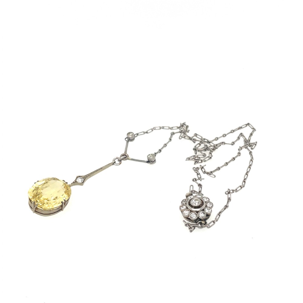 An Edwardian platinum pendant featuring an oval cushion-cut yellow sapphire suspended from a diamond-set drop chain. View III