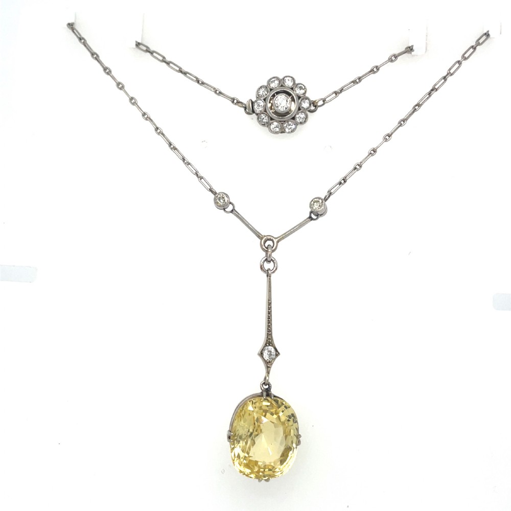 An Edwardian platinum pendant featuring an oval cushion-cut yellow sapphire suspended from a diamond-set drop chain. View VIII