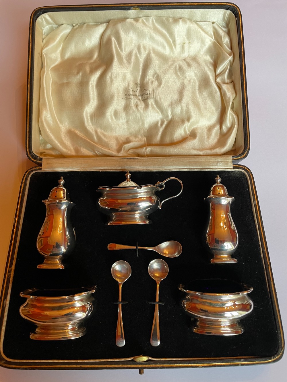 A cased sterling silver condiment set featuring two baluster pepper castors, two open salt cellars, a mustard pot, and three spoons inside a silk-lined box. View III