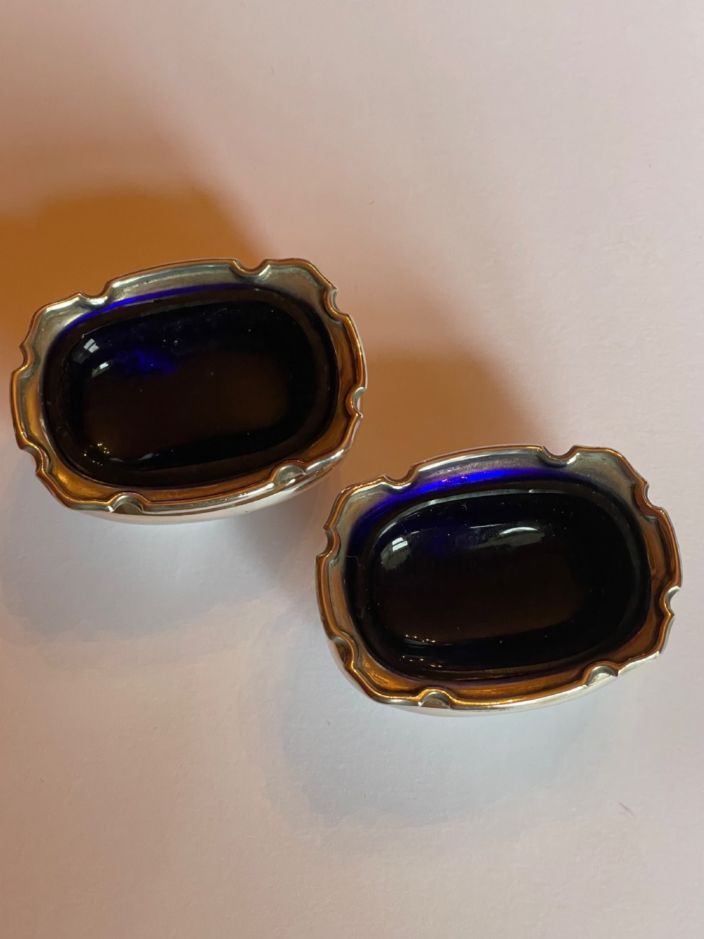 A cased sterling silver condiment set featuring two baluster pepper castors, two open salt cellars, a mustard pot, and three spoons inside a silk-lined box. View V
