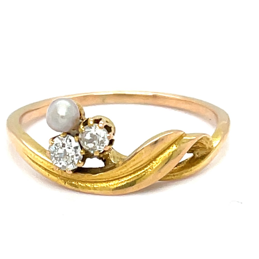 An Art Nouveau gold ring featuring a single white pearl paired with two diamonds on a sinuous flowing band.